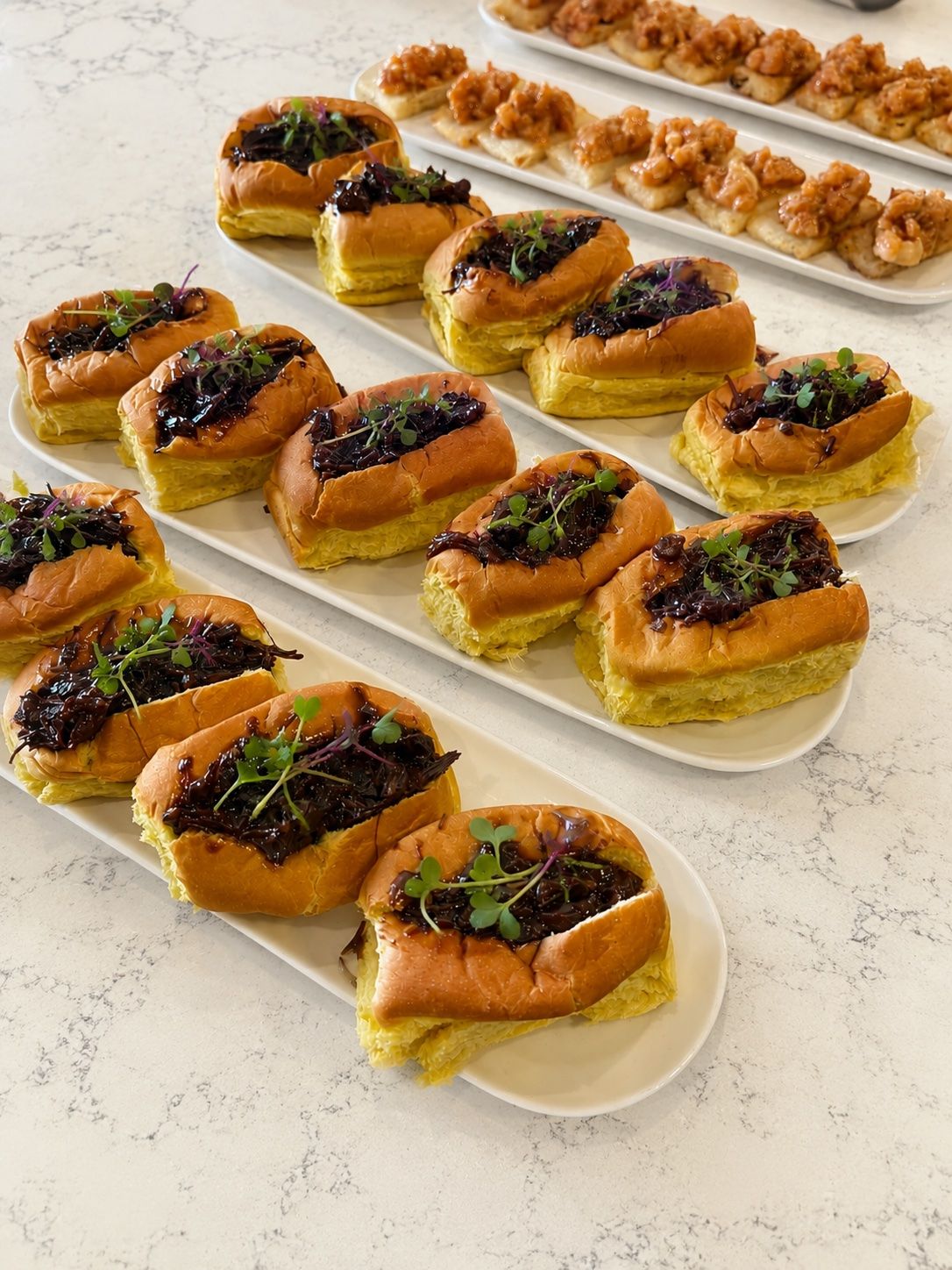 Mini brioche de carne melosa — Pan brioche tostado, carne guisada a fuego lento y brotes frescos. Servido en bandeja, listo para circular entre invitados.
