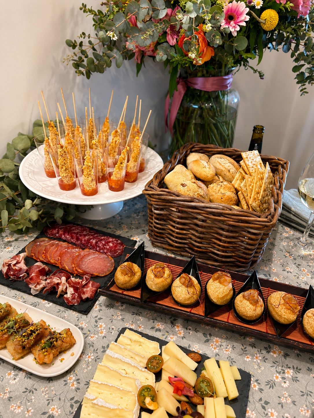 Mesa de aperitivo completa — Brochetas crujientes, tabla de ibéricos, quesos afinados, hojaldres y pan artesano. El buffet de aperitivo tal y como llega a un evento.