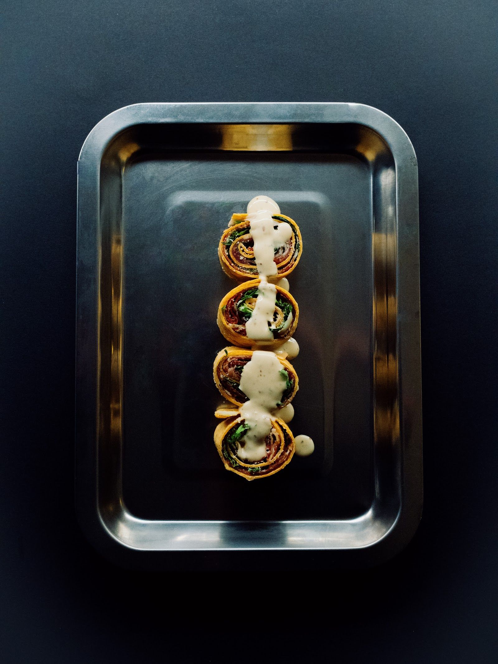Rollitos de tortilla con salsa de la casa — Servidos en bandeja, con un hilo de salsa cremosa.