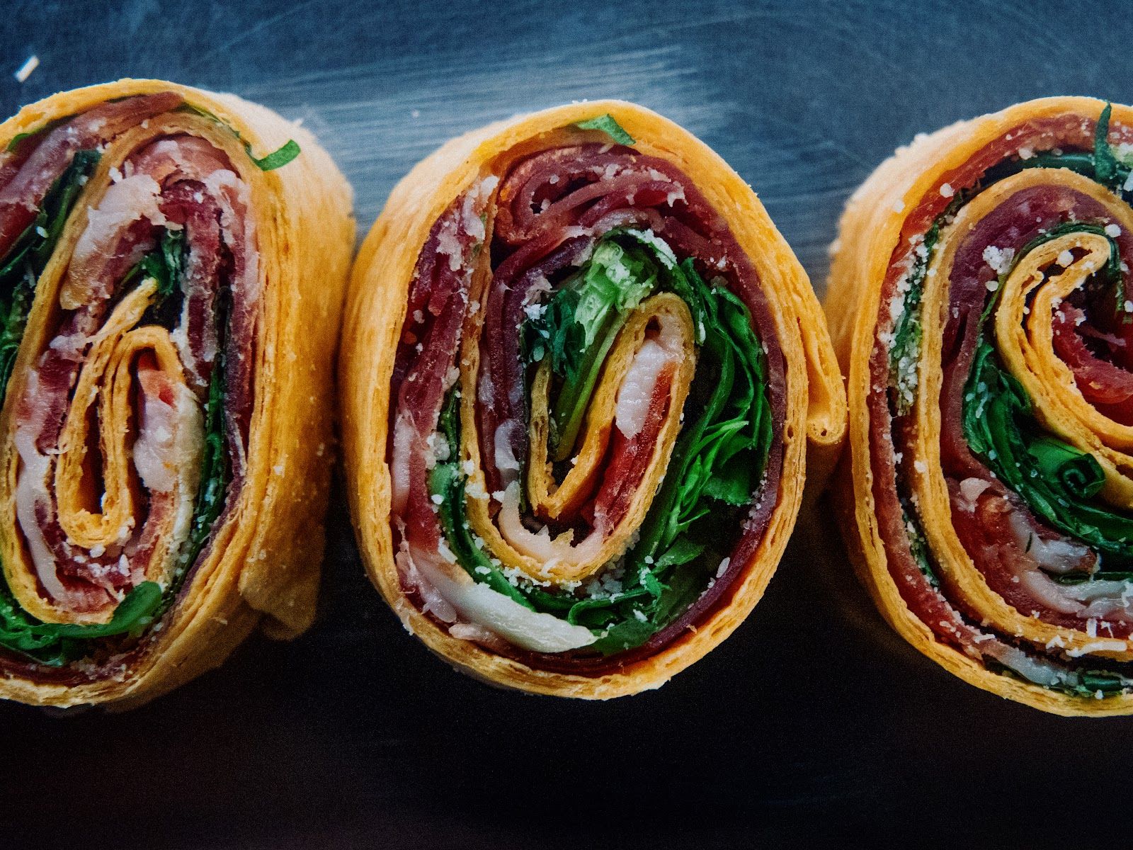 Rollito de tortilla, jamón y rúcula — Tortilla fina enrollada con jamón, rúcula fresca y queso.